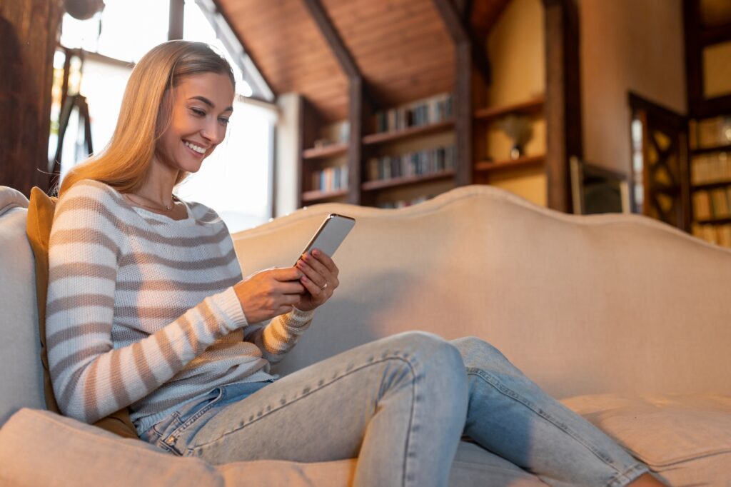 Portrait of smiling woman using smartphone at home